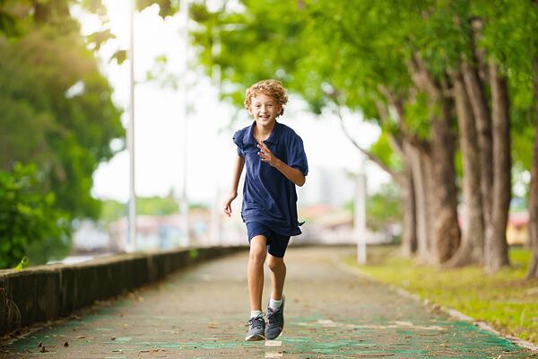 Chlapec běžící alejí 