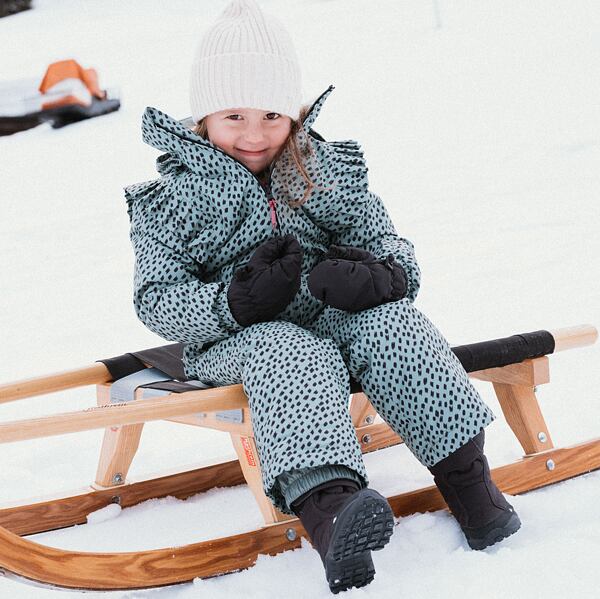 Holčička v zimních botách Protest sedí na saních