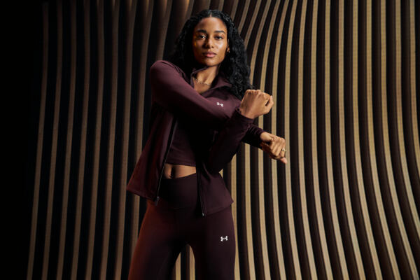 Žena v bordó setu Under Armour se protahuje